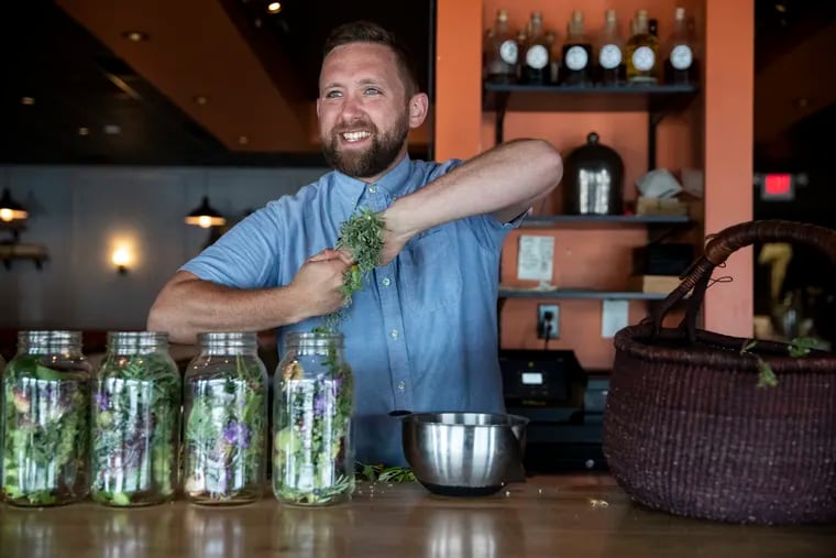 Danny Childs, bar manager at the Farm and Fisherman Tavern, fills jars with foraged botanicals in Cherry Hill, N.J., on Monday, July 12, 2021. Childs makes amari and other cocktails using foraged botanicals and plants from his garden.