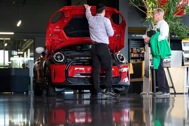 A salesperson shows an unsold 2024 Cooper SE electric hardtop to a prospective buyer in the showroom of a Mini dealership in May in Highlands Ranch, Colo.