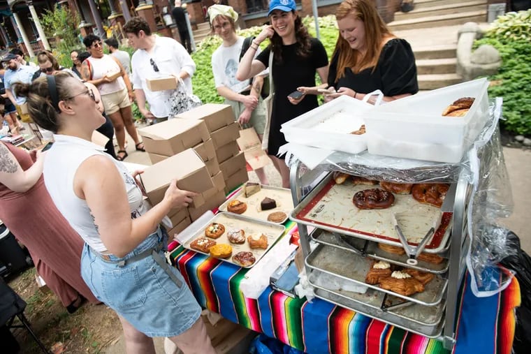 Emily Wilson (left) prepares orders for a line of customers during a neighborhood bake sale in West Philadelphia on Sunday, June 23, 2024. The line began 30 minutes before she opened and stretched down the block for the duration of the sale.