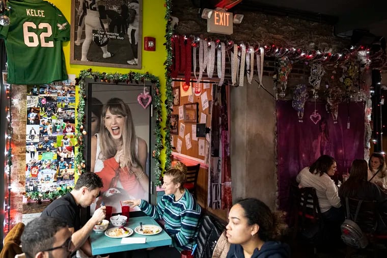 A framed poster of Taylor Swift at a Kansas City Chiefs game presides over diners at Taqueria Amor's Taylor Swift-themed pop-up in Manayunk. The pop-up — which runs through Feb. 25 — includes a shrine to the Kelce brothers and several Tayvis-related Easter eggs.