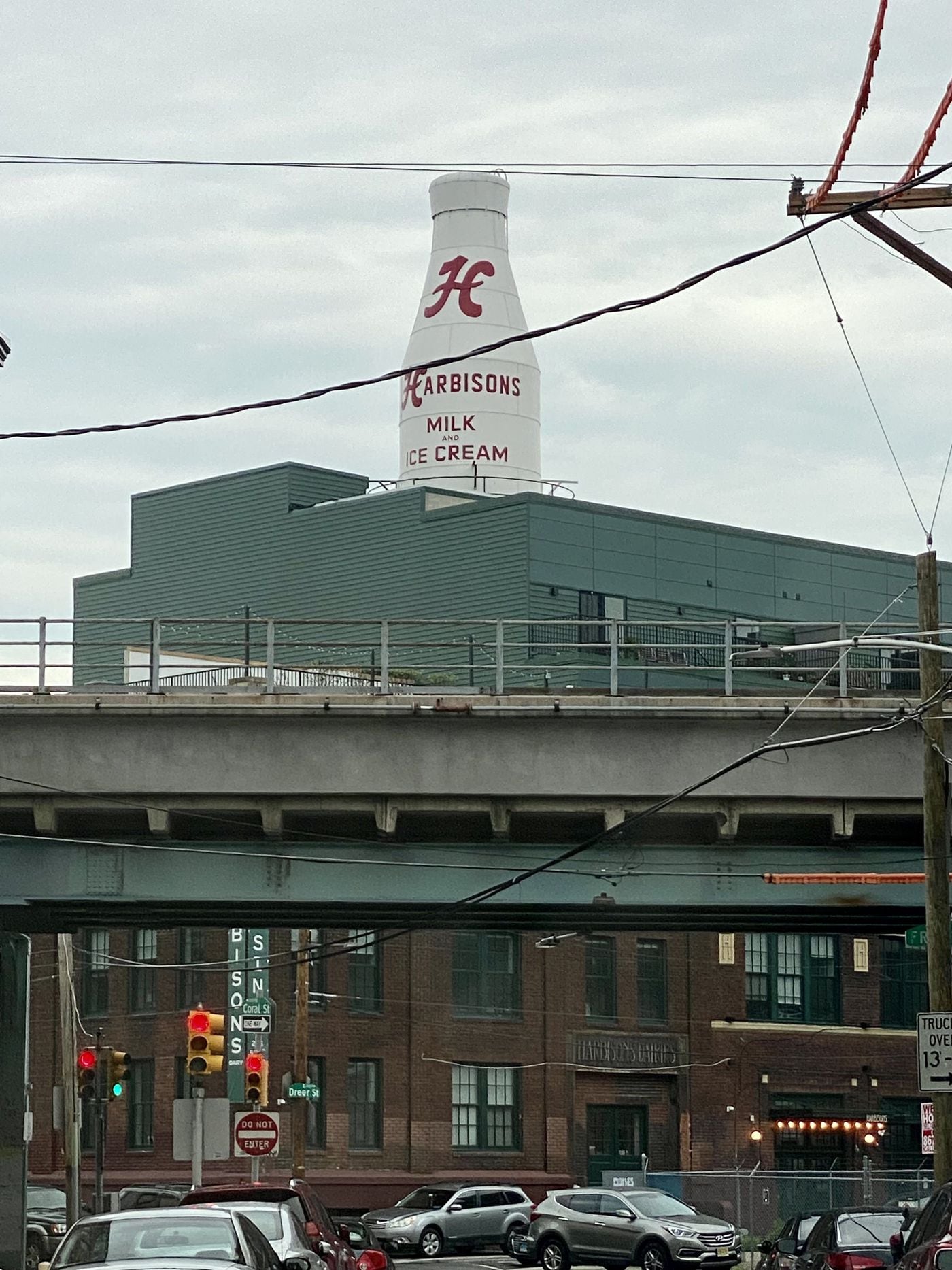 The Harbison's milk bottle, newly restored, rises over the building housing Forin Cafe in Kensington, near the Market-Frankford El tracks.