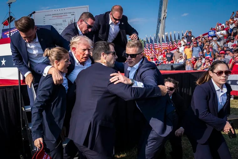 U.S. Secret Service agents remove former president Donald Trump from the stage after a shooting during a campaign rally in Butler, Pa.