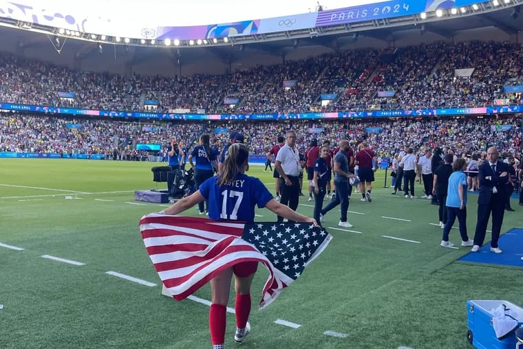 Sam Coffey carries the American flag after the U.S. defeated Brazil in women's soccer to win the gold medal on Saturday in Paris.