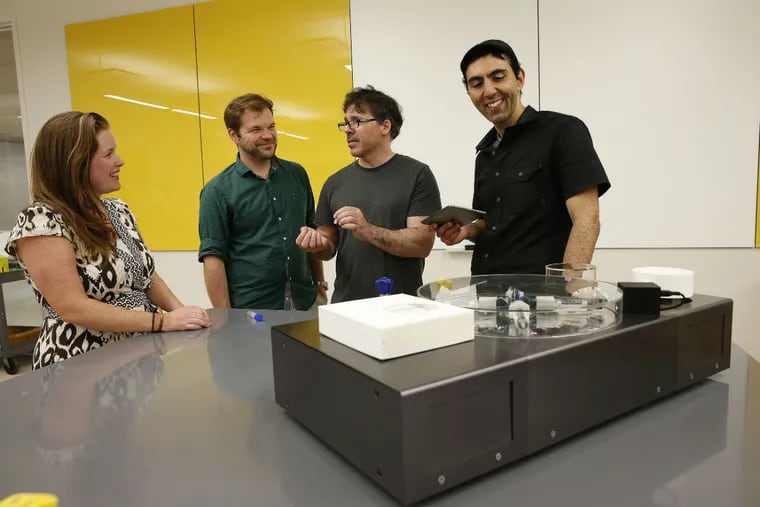 From left to right: Karen Hogan, Guz Gutmann, Michael Hogan, and Orkan Telhan have a discussion about the new automated, self-contained, countertop genetic engineering machine, they created, in foreground. They demonstrated it in a lab in the Levin Building in Philadelphia, Pa., on Aug. 2, 2016.