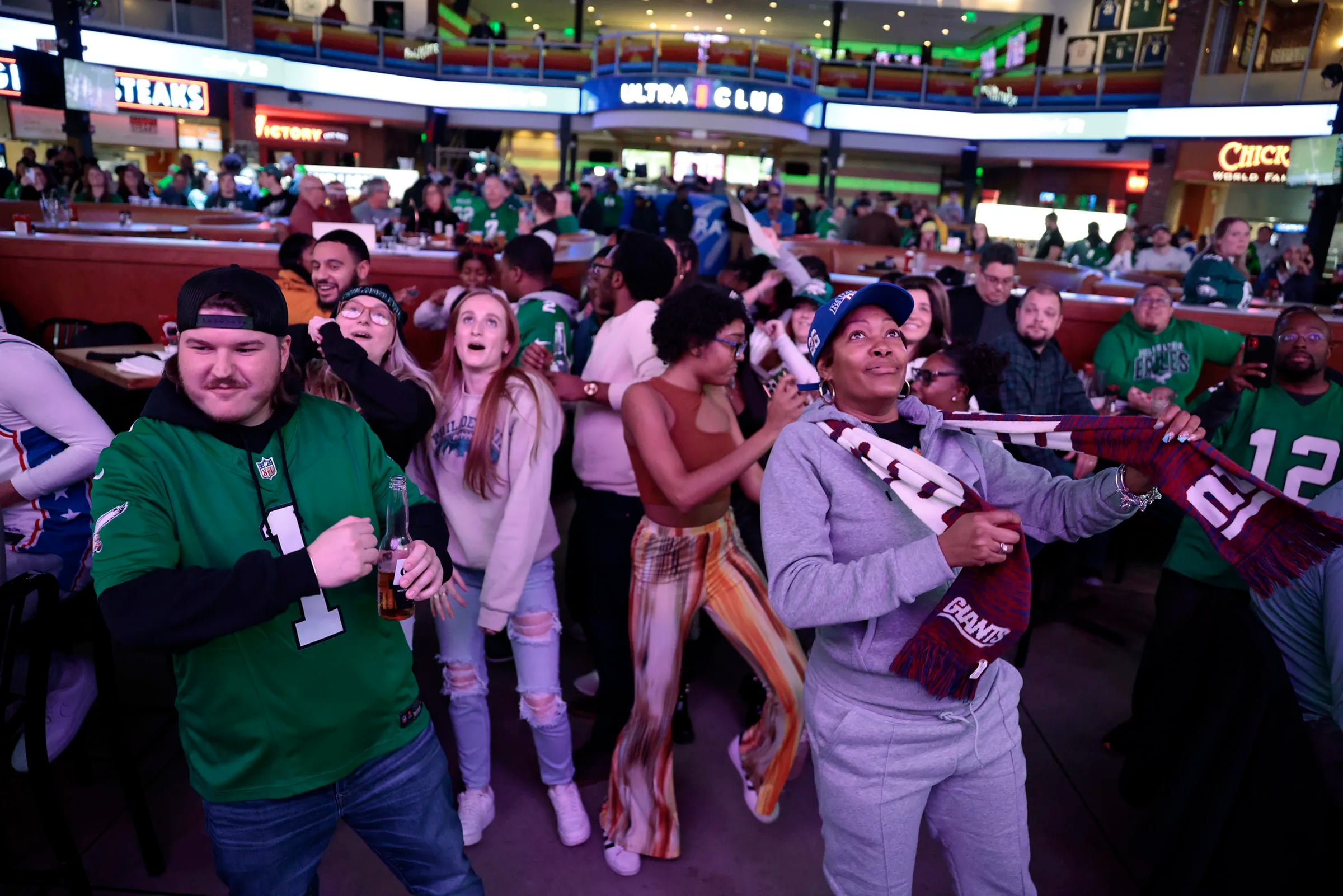 Eagles fan Ryan Reyes of Mullica Hill (front left) and Giants fan Lisa Storey (front right) of Philadelphia are among the fans who danced peacefully together during a commercial break while watching the Eagles at Giants NFL game at Xfinity Live! Philadelphia in Philadelphia, on Sunday, Jan. 7, 2024.