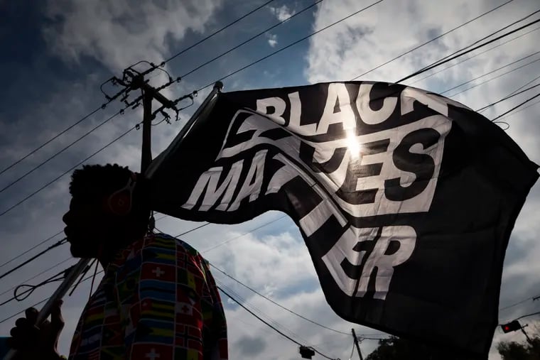 In this Dec. 12 photo, MD Crawford carries a Black Lives Matter flag before a march in La Marque, Texas to protest the shooting of Joshua Feast, 22, by a La Marque police officer.