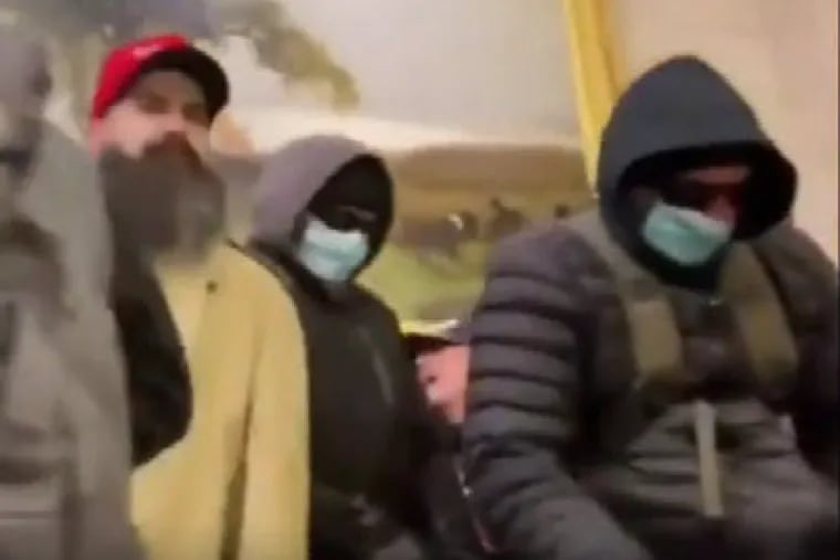 Stills taken from a social media livestream during the Jan. 6 Capitol riot show two men in surgical masks and hoodies who investigators have identified as Philip and David Walker. Prosecutors say this image, included in court filings, captures the moments before they attacked a New York Times photographer.