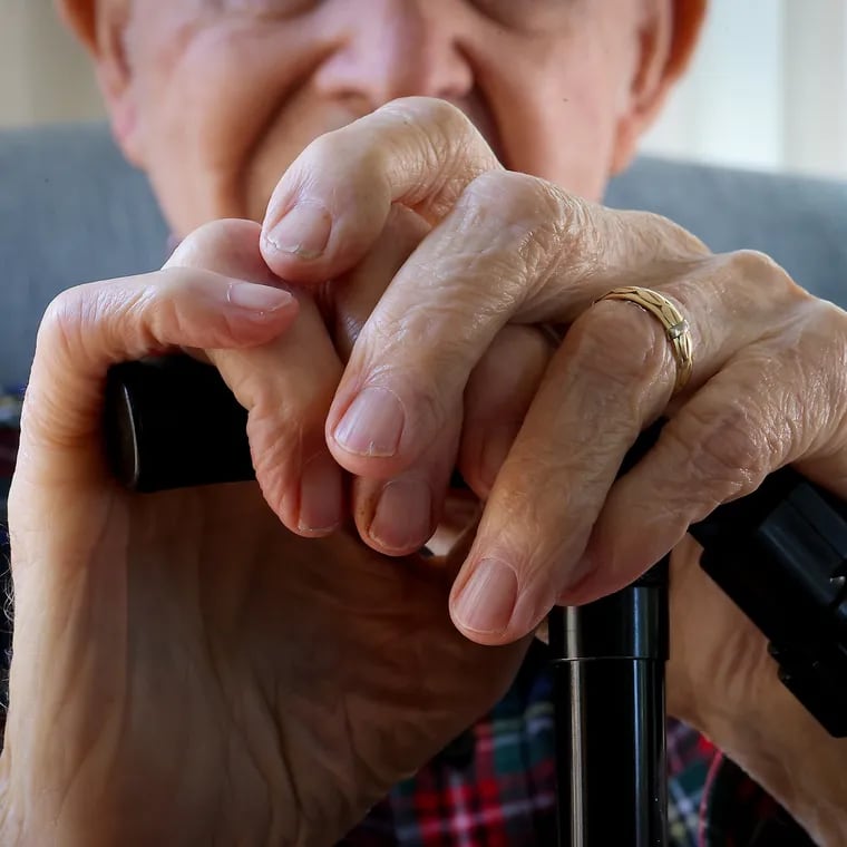 Charles Malloy, 99, rests his hands on his cane as he poses for a portrait at his home in West Chester on Wednesday, April 24, 2024.