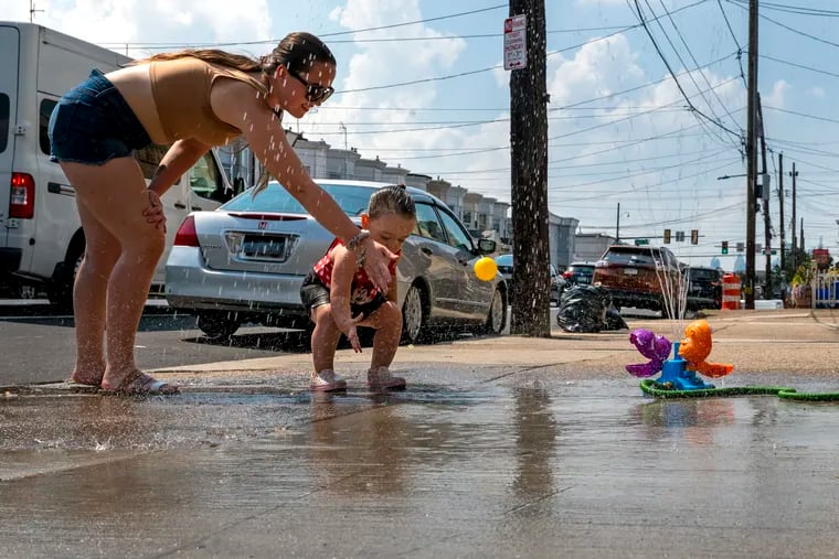Jocelyn Przepioski plays with her 2 year-old daughter Alayna on the sidewalk outside their home in Kensington in September during Philly's last heat wave.