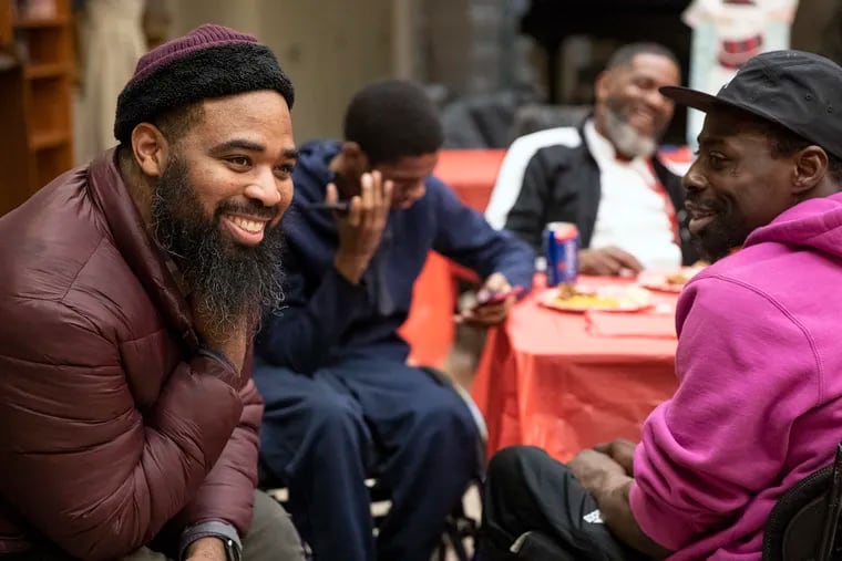 Jalil Frazier, left, laughs with John Muldrow, right, during the gunshot survivors group at the Carousel House in West Philadelphia on Monday, Dec. 16, 2019. The group was having a holiday party for its final meeting of the year.