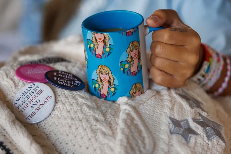 Annie Wu Henry, campaign manager for Swifties for Kamala, holding a coffee cup with images of Taylor Swift on it at her home in Fishtown.