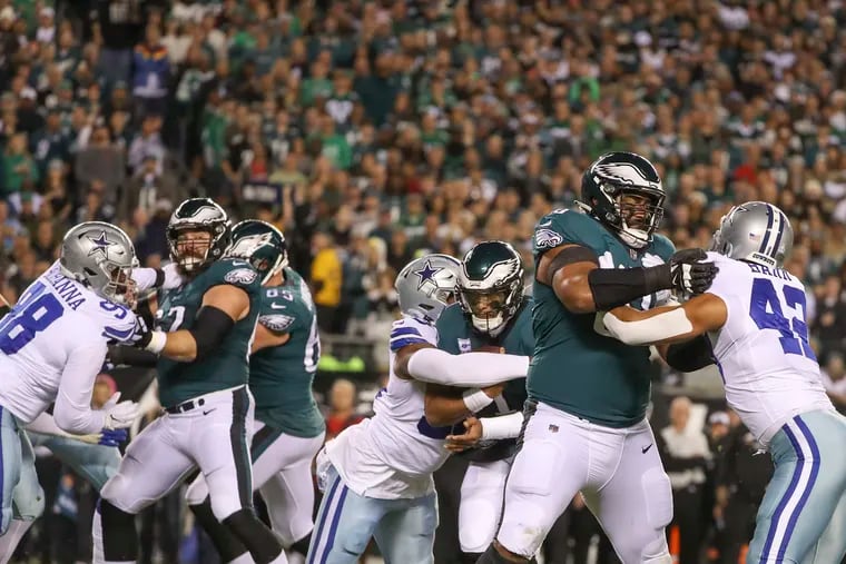 Eagles center Jason Kelce (62) and tackle Jordan Mailata (68) block for quarterback Jalen Hurts (1), who is eventually brought down by Cowboys defensive end Chauncey Golston (99), during the Eagles' 26-17 victory Sunday night.