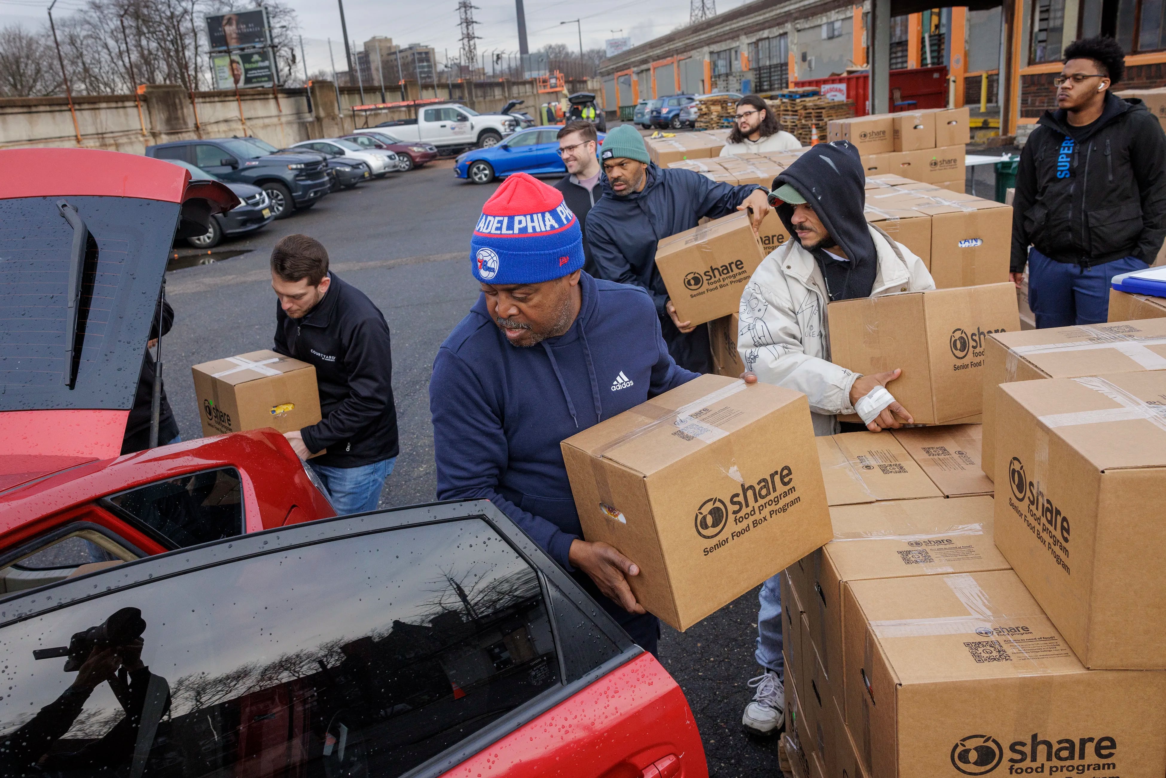 In foreground is George Moody, a volunteer for the past three months loading a DoorDash car with food for seniors in February. Share Food Program in Hunting Park is among the largest DoorDash operations in the world.