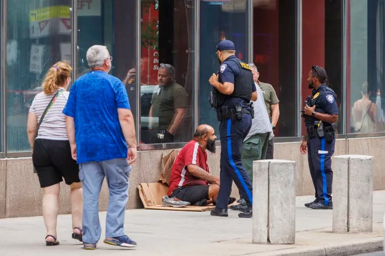 Jefferson police speak with a man who was sleeping on the street at North 11th Street at Filbert Street in Center City in July.