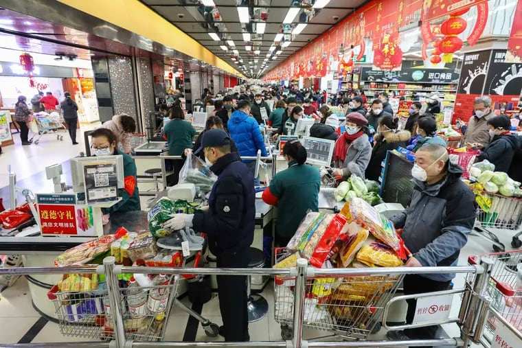 Shoppers wearing face masks pay for their groceries at a supermarket in Wuhan in central China's Hubei province, Saturday, Jan. 25, 2020.