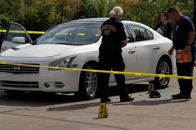 Philadelphia Crime Scene Unit investigators examine a car involved in a shooting at a gas station in West Philadelphia on Sunday, where a 19-year-old died after being shot eight times.
