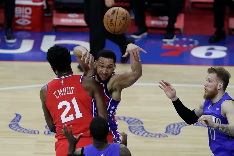 Sixers guard Ben Simmons passes the basketball past teammate center Joel Embiid against Magic guard Dwayne Bacon and forward Ignas Brazdeikis.