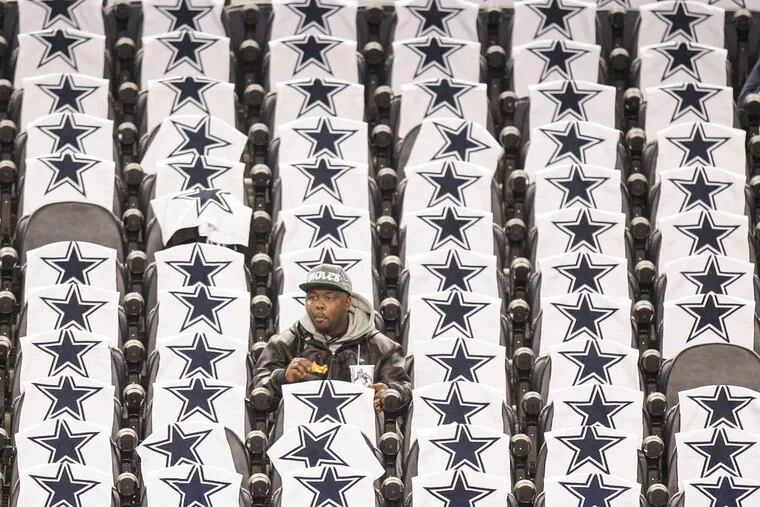 STEVEN M. FALK / STAFF PHOTOGRAPHER An Eagles fan snacks and waits for kickoff surrounded by Cowboys towels yesterday at AT&amp;T Stadium.