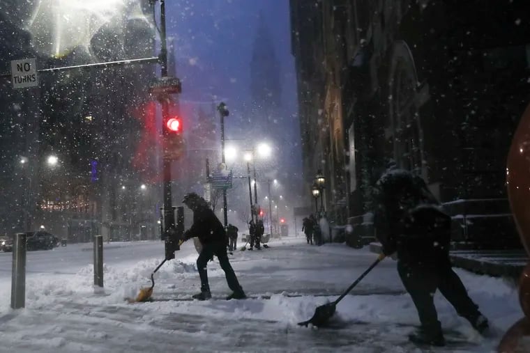 A group of people shovel the street by Broad and Cherry streets in Philadelphia while heavy snow falls on Wednesday, Dec. 16, 2020. The region is currently under a Winter Storm warning.