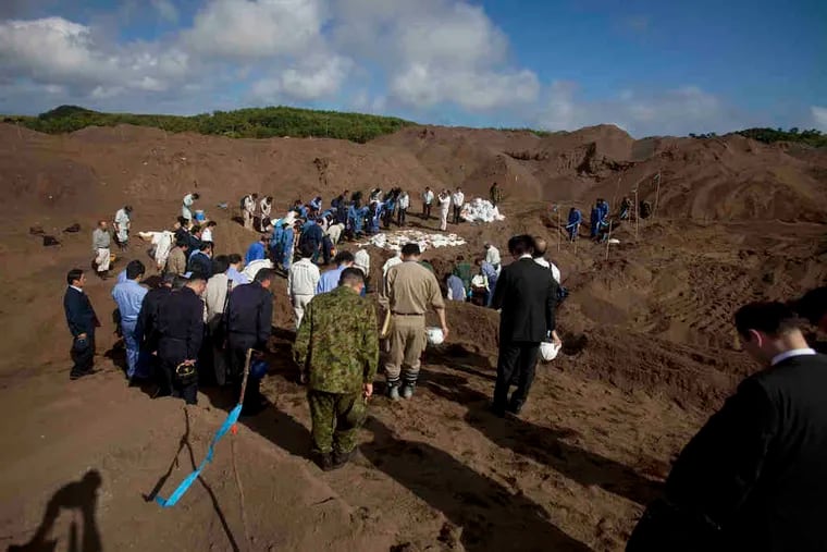 Japanese officials bow at a mass grave site on Iwo Jima, where the remains of Japanese soldiers from WWII have been discovered.