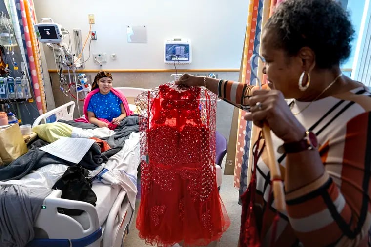 Antoinette Miller, 68, holds up dress choices for her granddaughter Taj Harris (left), 19, in her room at Children’s Hospital of Philadelphia on June 12, before attending CHOP’s annual Joshua Kahan Fund Prom. The annual event is designed to provide sick kids with a mental boost.