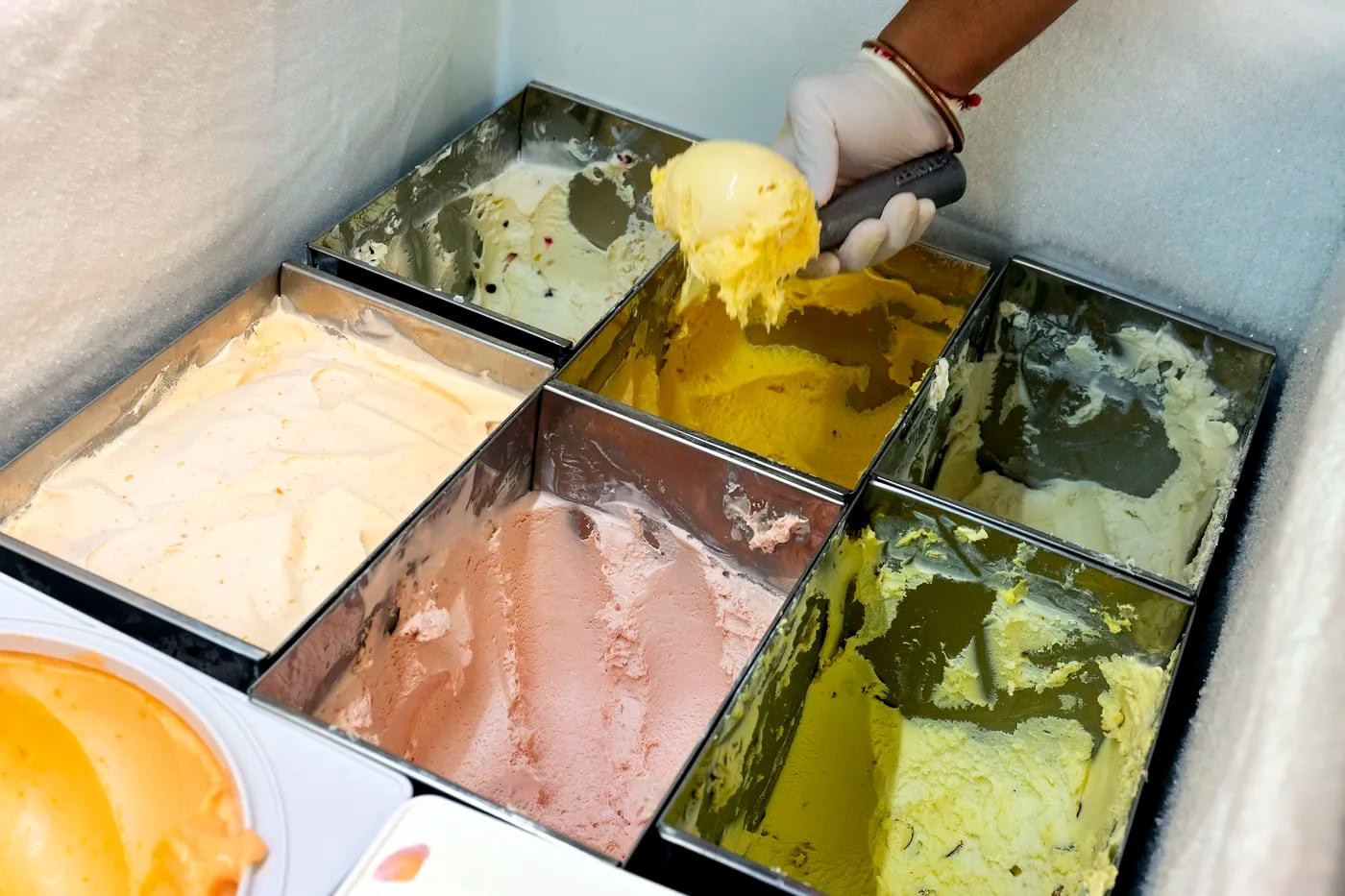 Jay Patel scoops homemade ice cream at Ice Cream Station. The Patel family has begun churning several fresh ice creams that remind them of home. 