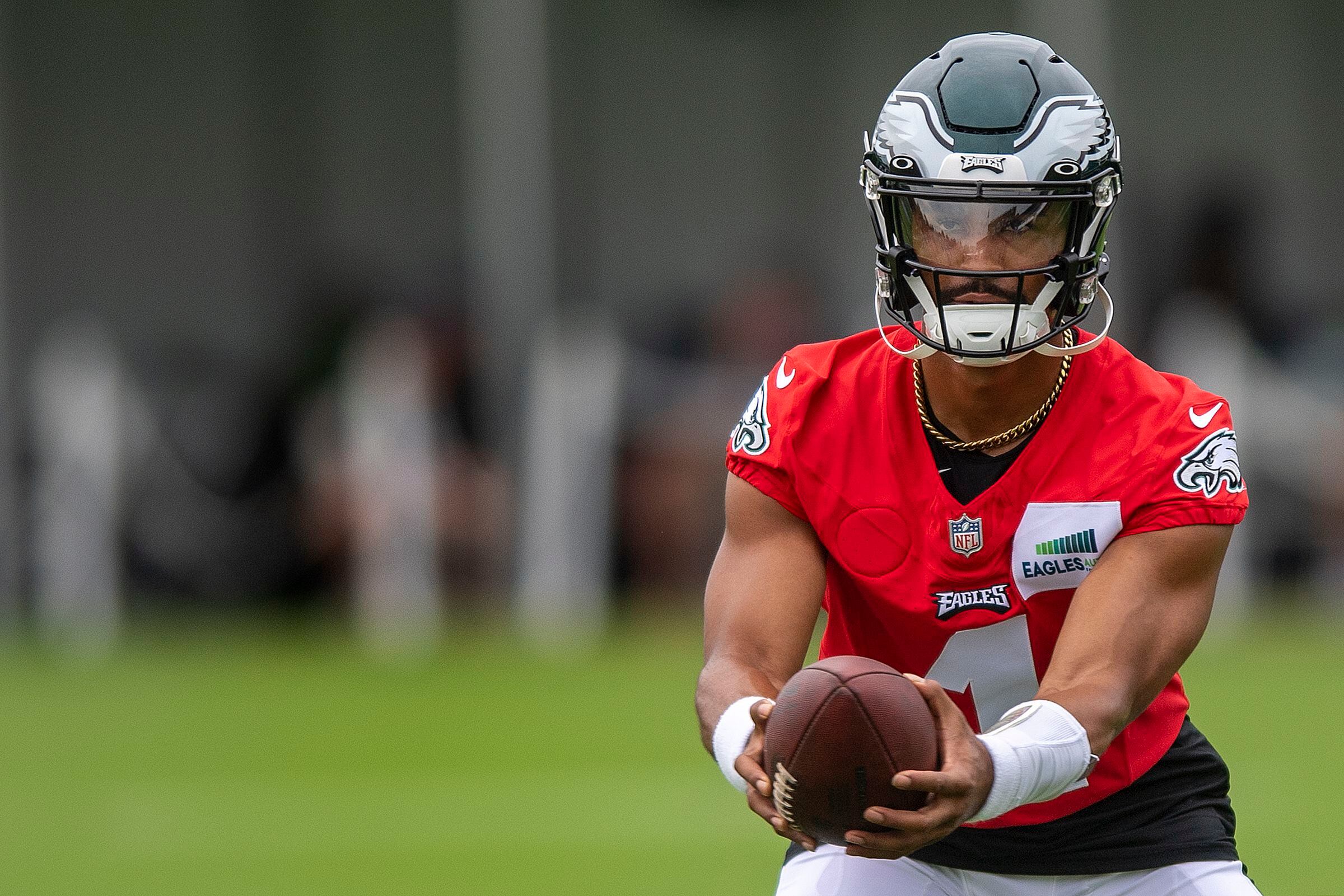 Philadelphia Eagles' Jalen Hurts, right, poses with the fan who received  his signed practice jersey with her two twins during practice at an NFL  football training camp, Sunday, July 30, 2023, in