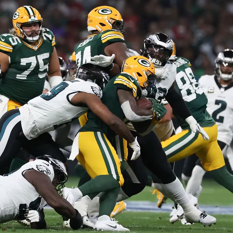 Eagles cornerback Darius Slay (right) looks on as linebacker Josh Sweat and defensive tackle Jordan Davis stop Green Bay Packers running back Josh Jacobs on Friday.