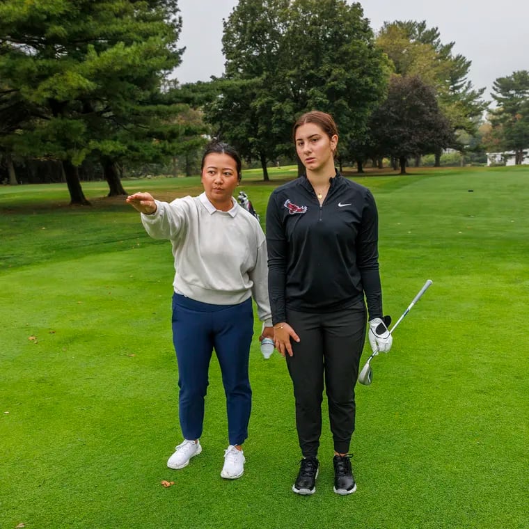 St. Joe's women's golf coach Theresa Luu looks over the green at first hole with freshman Ava Tornello at the Bala Golf Club.