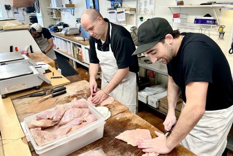 New owner Rob Passio (center) and worker Vince Lombardi, grandson of the founder, slice chicken cutlets at Lombardi's Prime Meats, 1801 Packer Ave.