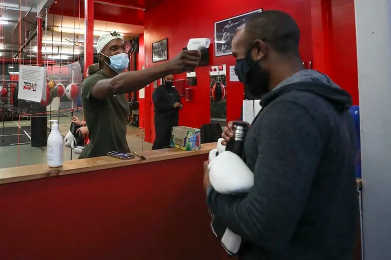Maleek Jackson (left) takes Dariq Cobb’s temperature at Maleek Jackson Fitness Boxing Gym in the Northern Liberties neighborhood of Philadelphia on Wednesday, Oct. 21, 2020.