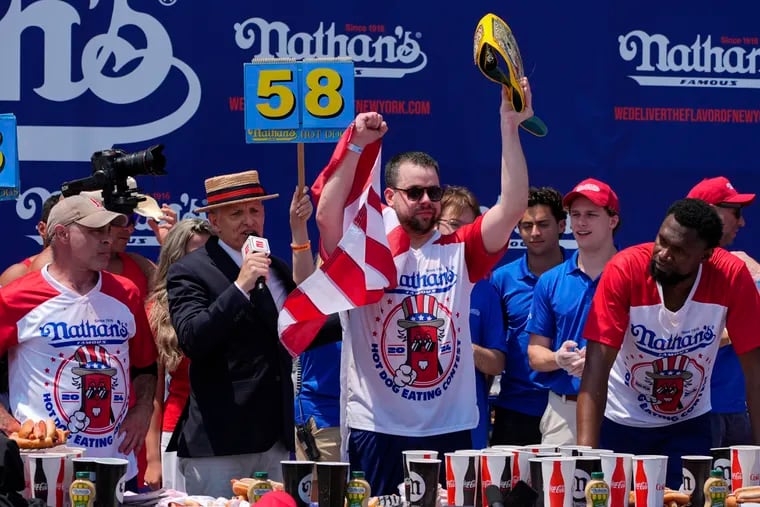 Patrick Bertoletti, center, reacts after winning the men's division in Nathan's Famous Fourth of July hot dog eating contest on July 4, 2024, at Coney Island.