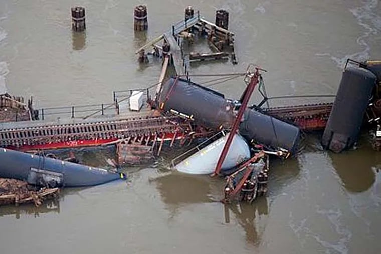 Several cars lay in the water after a freight train derailed in Paulsboro, N.J., Friday, Nov. 30, 2012. People in three southern New Jersey towns were told Friday to stay inside after the freight train derailed and several tanker cars carrying hazardous materials toppled from a bridge and into a creek. (AP Photo/Cliff Owen)
