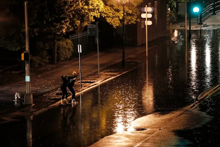 Two people jump into the high water at Delaware Avenue and Federal Street in Camden. They were caught in heavy rains in late May. More downpours are expected late Friday.