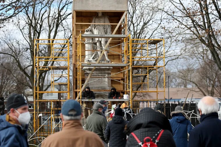 A team from Angelo's Marble & Granite Inc. inspect the condition of the Christopher Columbus statue in Marconi Plaza in Philadelphia on Jan. 27, 2021, when the box covering the statue was temporarily removed for the inspection.