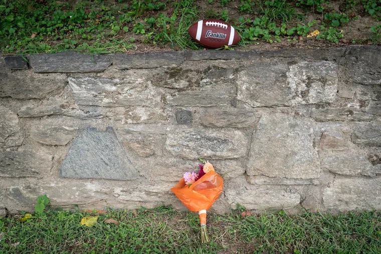 Flowers and a football sit outside of Roxborough High School near the football field at the end of the school day Wednesday.