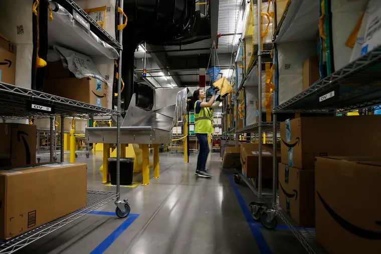 In this Dec. 17, 2019, photo Jocelyn Nieto stows packages into special containers after Amazon robots deliver separated packages by zip code at an Amazon warehouse facility in Goodyear, Ariz. Companies that order, pack and ship goods are moving up seasonal hiring earlier in the year and converting gig positions to full-time roles at a faster clip than before. (AP Photo/Ross D. Franklin)