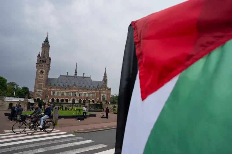 A lone demonstrator waves the Palestinian flag outside the Peace Palace, rear, housing the International Court of Justice in The Hague, Netherlands, Friday, May 24, 2024.