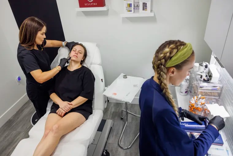 Aesthetic Nurse Practitioner Sarah Sidiqi prepares Julia O'Reilly for her fillers. O'Reilly lost 50  pounds on Ozempic and misses her fuller face. At right is medical assistant Courtney Brady.