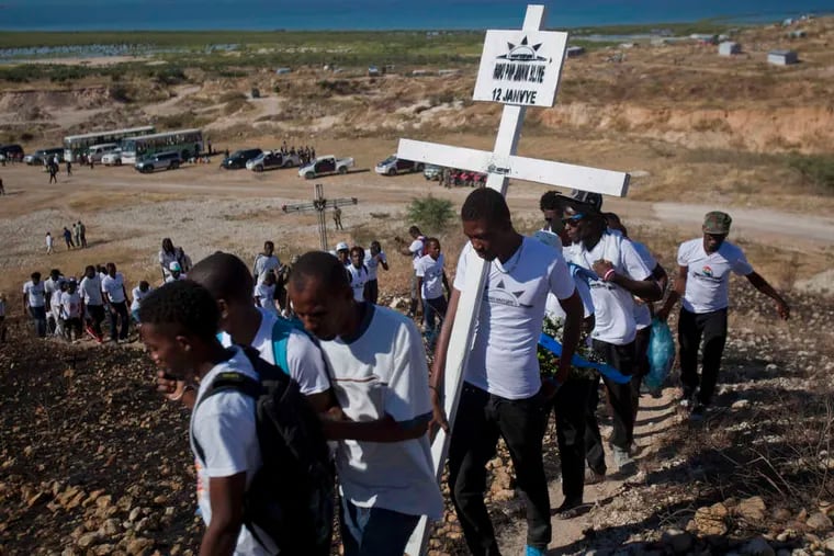 Relatives of those who died in the 2010 earthquake carry a cross to be placed on a hilltop. The previous administration estimated that 316,000 people were killed, but the exact number is unclear.