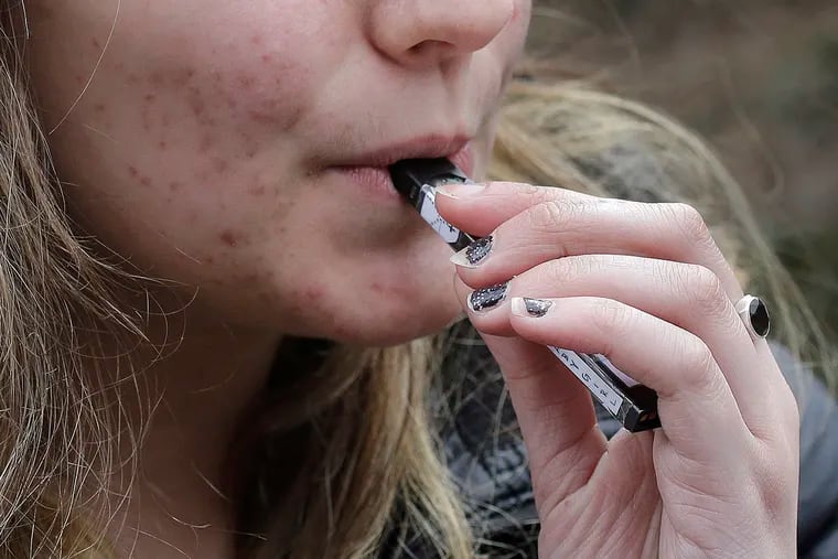 A high school student uses a vaping device near a school campus in Cambridge, Mass. on April 11, 2018. Massachusetts Gov. Charlie Baker declared a public health emergency  Sept. 24, 2019, ordering a four-month temporary ban on all vaping products in the state.
