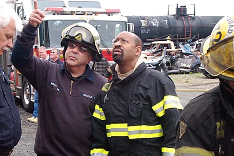Mayor Nutter looks on as Fire Fighter Louis Brasted gives him instruction before entering a simulated building collapse. (David Kearney)