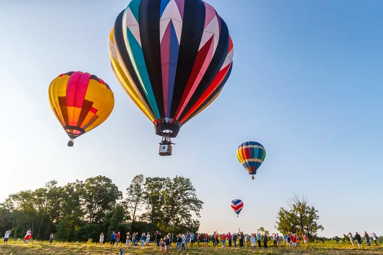 A balloon passenger waves to those gathered on the grounds of the New Garden Flying Field in Toughkenamon PA,  as several balloons took off for a sunrise flight as part of the 13th Annual Chester County Balloon Festival on June 23, 2019. The festival returns this weekend.