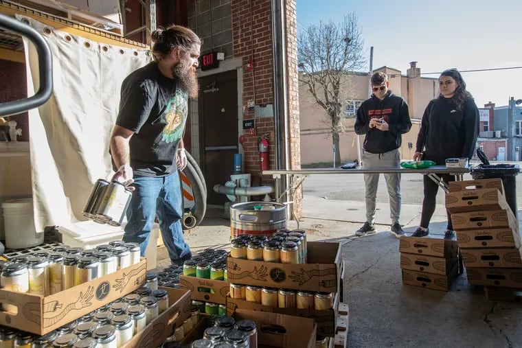 Steve Buller (left) a bartender at Tired Hands Brewing Company in Ardmore, grabs the beer selection for customers in March. Breweries and distillers are one of the many Pennsylvania industries that could benefit from the 2020 stimulus plan just passed in Congress.