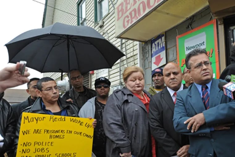 Outside the Bernard Grocery at 27th and Pierce in Camden, mourners and politicians try to make sense of the shooting that took the life of owner Miguel Almonte.  Here, politicians, including Assemblyman Angel Ortiz, right; and Camden City Council president Frank Moran, next to him, call for a state of emergency in Camden.  12/06/11 (  APRIL SAUL / Staff Photographer )