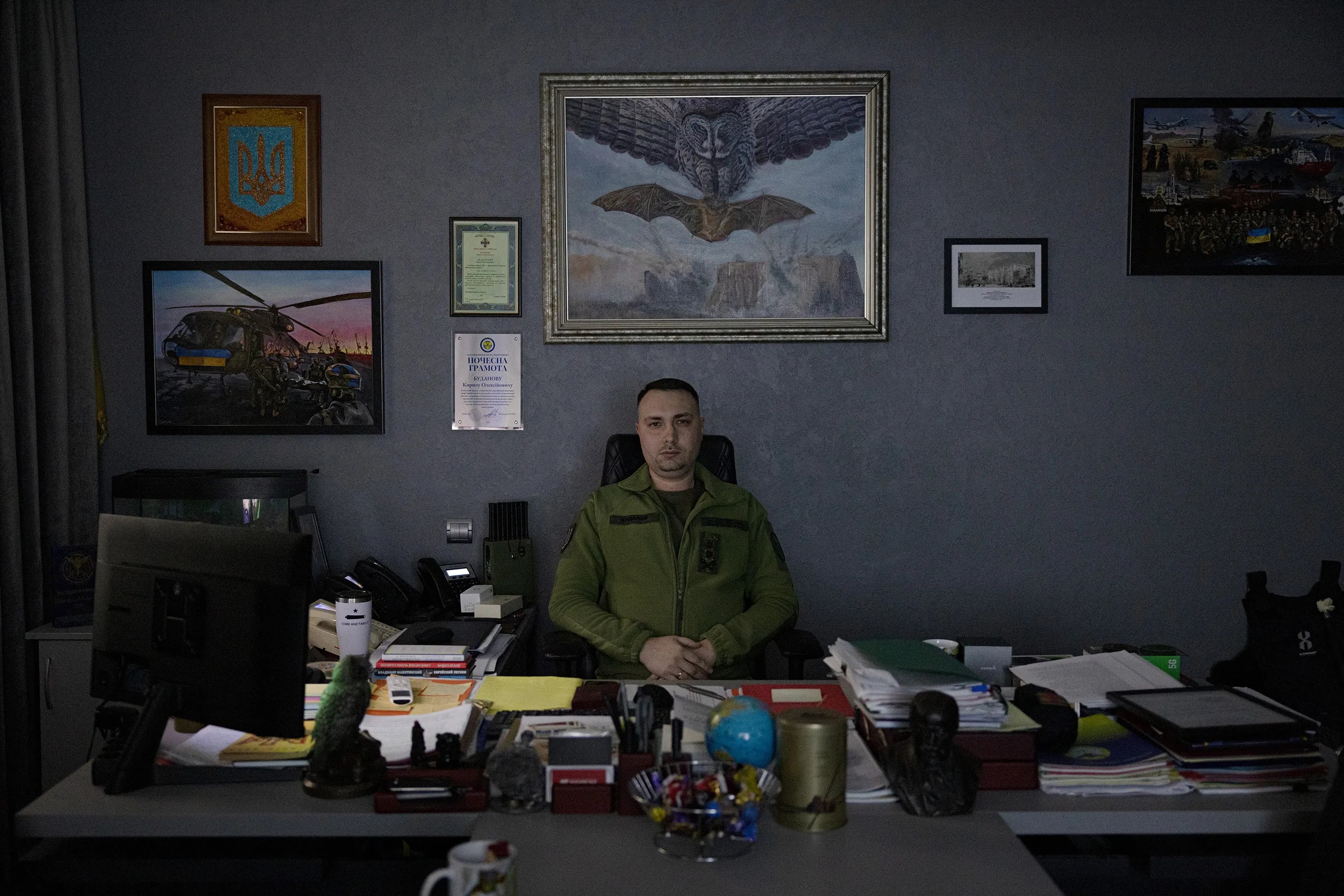 Lt. Gen. Kyrylo Budanov, Ukraine's 38-year-old spymaster, at his desk. Behind him is a large painting of an owl sinking its claws into a bat. The military intelligence agency adopted the owl as its symbol in 2016, two years after Moscow invaded Crimea, to troll the Russians. The bat is the symbol of Russia’s premier special operations unit, the Spetsnaz.