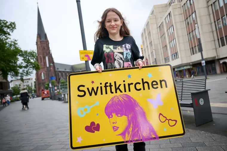 Aleshanee Westhoff shows a "Swiftkirchen" town sign in honor of musician Taylor Swift in Gelsenkirchen, Germany, on Tuesday.
