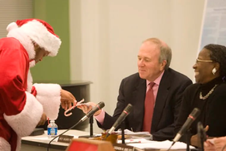 Student Lawrence Jones-Mahoney, dressed as Santa, presents candy canes yesterday to James Gallagher and Cassandra Jones at an SRC meeting, along with a wish list for better schools.