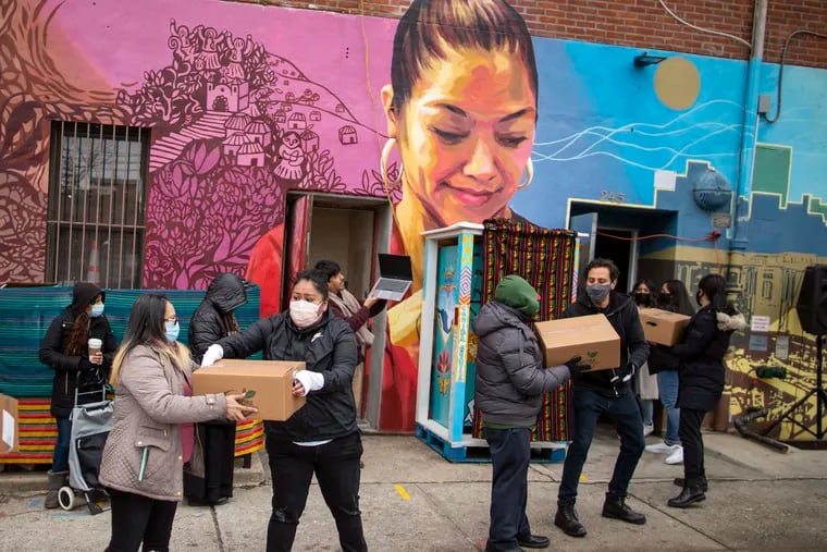 Here in 2021, volunteers carry food for donations as people receive COVID-19 information for vaccines at the community center Mixteca in the Brooklyn borough of New York. Latinos in the U.S. were hard hit by the pandemic both financially and personally, but many feel generally optimistic that the worst is behind them, according to a new study by the Pew Research Center.