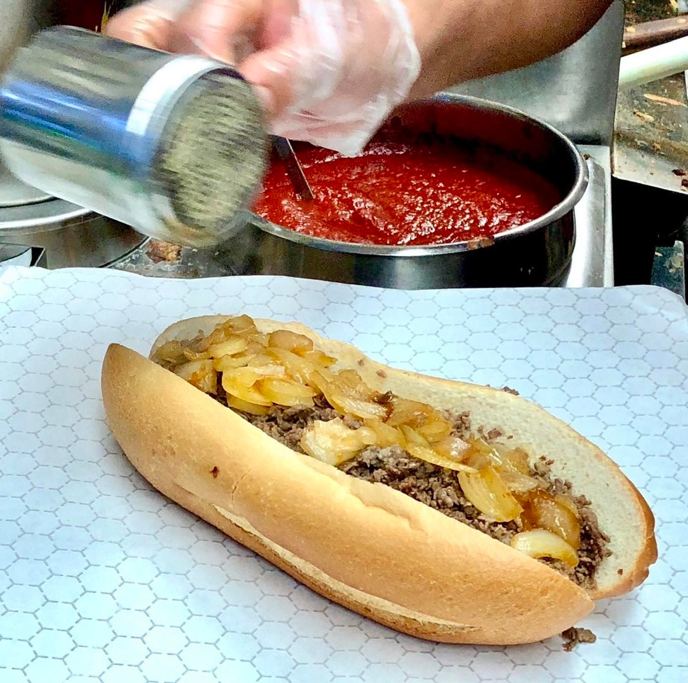 A cheesesteak gets a finishing sprinkling of pepper at Dalessandro's.